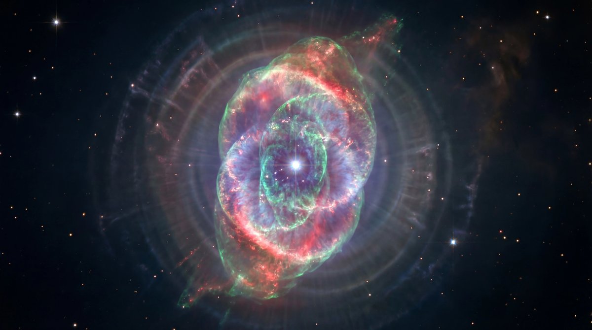 Vibrant Cat's Eye Nebula featuring complex glowing shells of gas and a bright central star in deep space.
