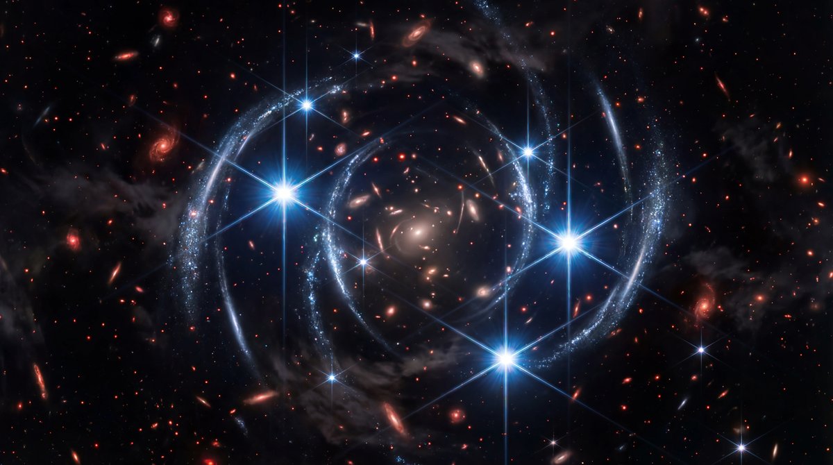 Galaxy cluster bending light to reveal mirrored star clusters and bright massive stars against a dark, starry cosmos.