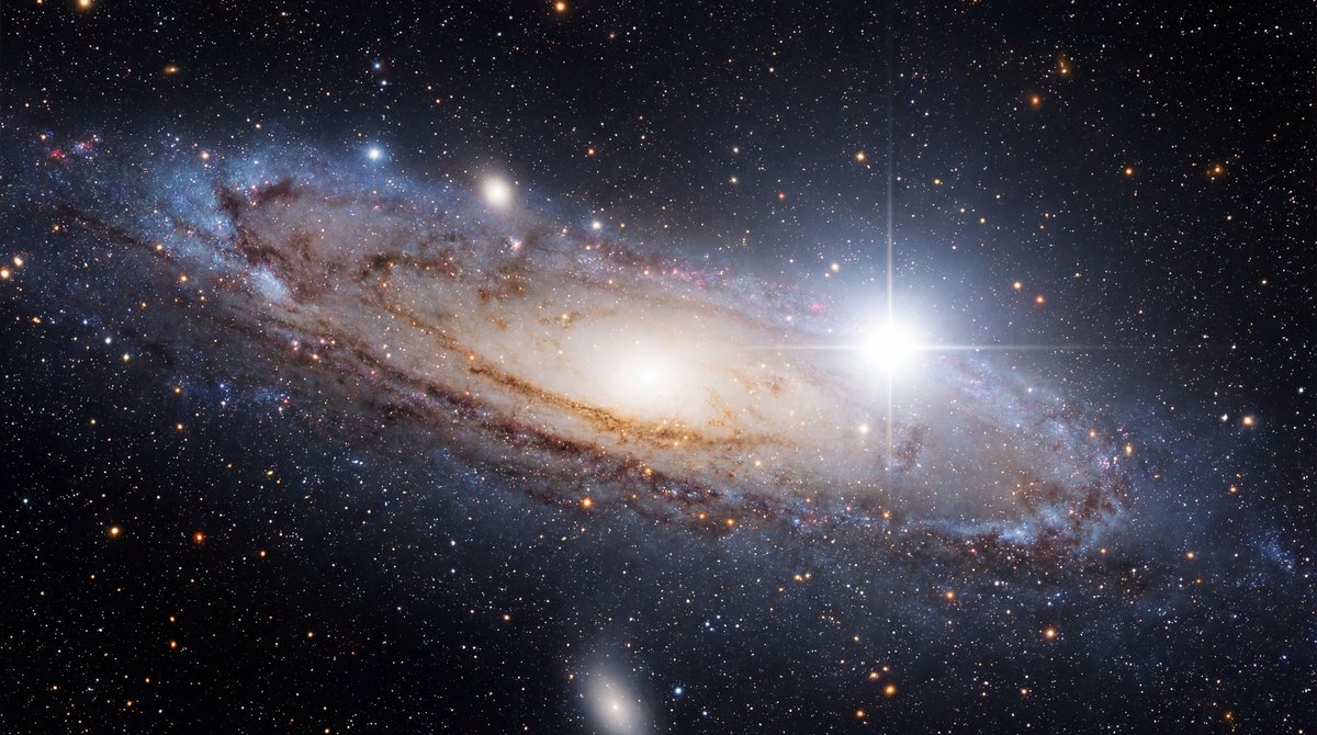 Brilliant white supernova explosion within a colorful spiral galaxy against a deep black starry cosmos.