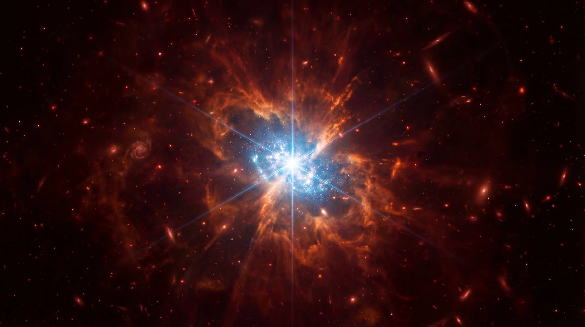 A brilliant galaxy emitting intense light into the dark universe, framed by colorful distant stars and diffraction spikes.