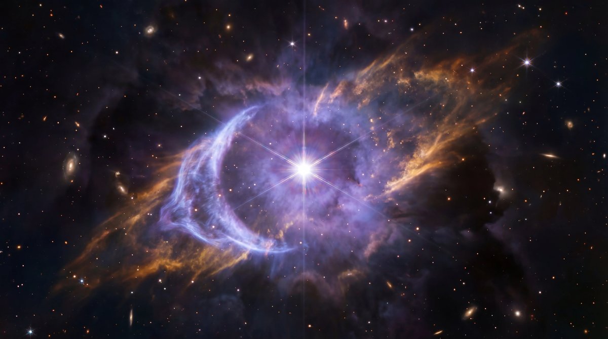 A bright star surrounded by a glowing blue and gold bubble of gas and dust pushing against dark starry space.